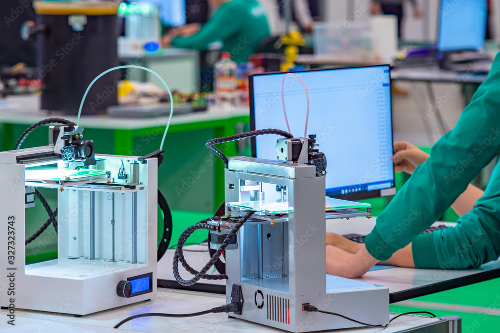 Poster 3d printers are on the table. teenagers set parameters for printing three-dimensional images. techni