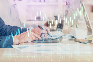 Forex graph with businessman working on computer in office on background. Concept of hardworking....