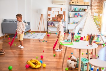 Adorable blonde twins playing around lots of toys at kindergarten