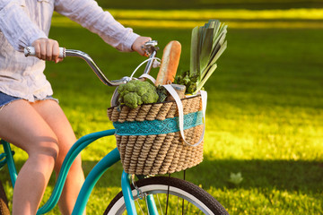 Woman riding a bicycle with vegetarian products in basket
