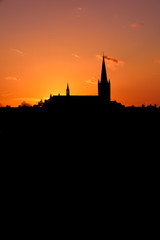 Church building exterior in silhouette of sunrise or sunset with glowing sunlight