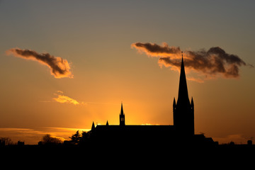 Church building exterior in silhouette of sunrise or sunset with glowing sunlight
