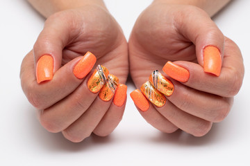 Brightly orange sequin manicure with gold falcon, black and white cobweb with crystals on long square nails closeup on a white background. Orange manicure. Solar nails. Summer.
