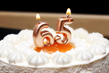 Burning candles in the form of numbers 65 on a birthday cake. Symbol of old age.