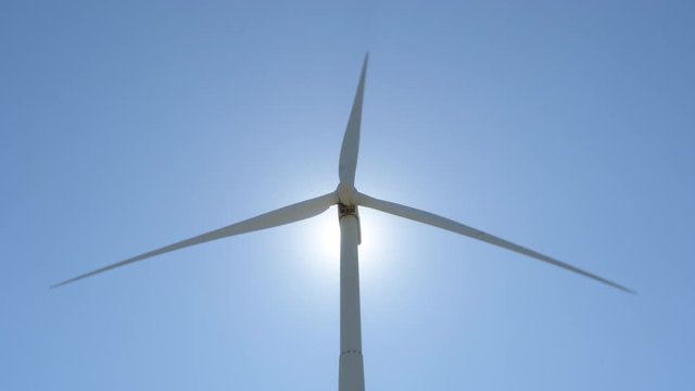 Wind turbine of renewable energy moving at backlight with blue sky a sunny day