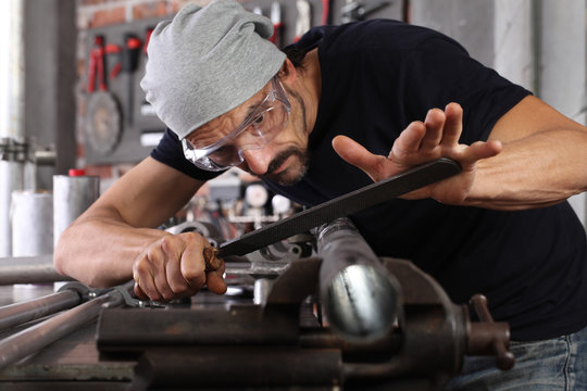 Man Work With File Rasp Metal Iron Pipe Gripped In Vice On Workbench Table In Garage Workshop, Do It Yourself Concept, Hands Close Up