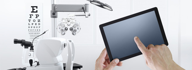 eye examination test concept, hands touch screen of digital tablet, ophthalmology and optometry equipment on background