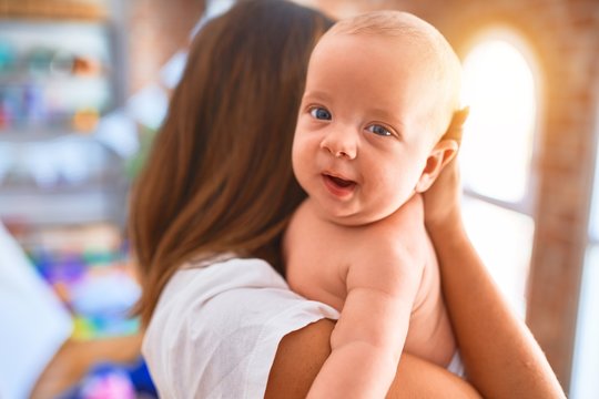 Young beautifull woman and her baby standing at home. Mother holding and hugging newborn