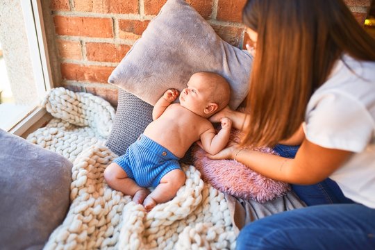 Young beautifull woman and her baby on the floor over blanket at home. Newborn and mother relaxing and resting comfortable