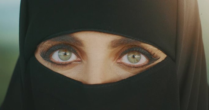 Portrait of a muslim woman wearing traditional black niqab showing only her green eyes, middle east culture