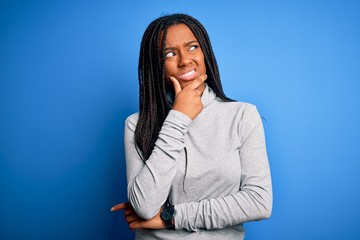 Young african american woman standing wearing casual turtleneck over blue isolated background Thinking worried about a question, concerned and nervous with hand on chin