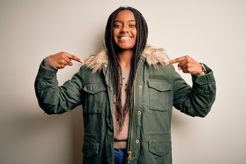 Young african american woman wearing winter parka coat over isolated background looking confident with smile on face, pointing oneself with fingers proud and happy.