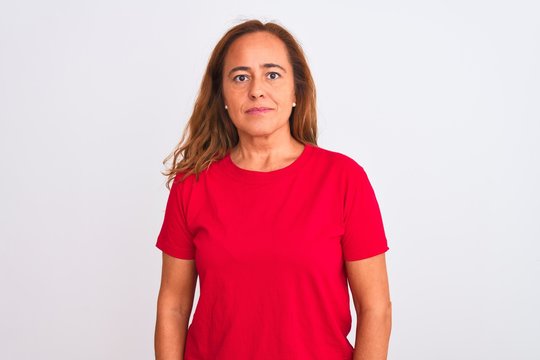 Middle age mature woman standing over white isolated background Relaxed with serious expression on face. Simple and natural looking at the camera.