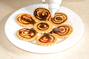 Chocolate decorated cookies laid out on a white plate. A cup of coffee.
