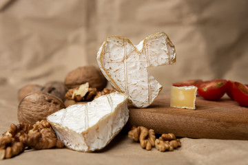 Obraz na płótnie Canvas Neufchatel, French cheese made in Normandy from cow's milk. with walnut kernels and cherry tomatoes on a wooden wooden background. Copy space white mold growing