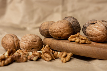 walnuts on a background of craft paper on a wooden plate. whole and chopped. place for text