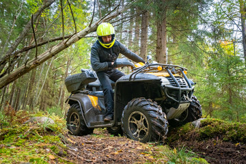 ATV. A man looks at the wheels of a Quad bike. Journey through the forest on a Quad bike. A man...