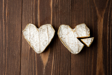 Neufchatel, French cheese made in Normandy from cow's milk on a wooden background. place for text. two pieces in the shape of a heart