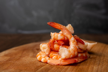 boiled peeled king prawns laid out on a slide on a concrete background on a wooden plate. place for text