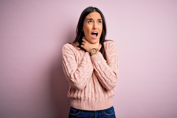 Young beautiful brunette woman wearing casual sweater over isolated pink background shouting suffocate because painful strangle. Health problem. Asphyxiate and suicide concept.