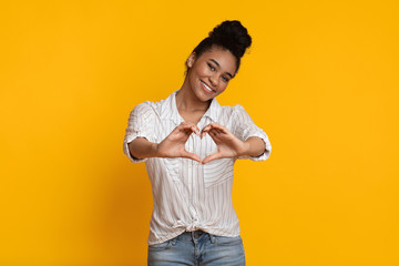 Fototapeta na wymiar Positive Romantic Afro Girl Shaping Hands Like Heart On Yellow Background