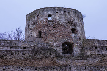 The ruines of old ancient medieval fortress or castle with turret or tower and brick, cobble or stone wall in the cloudy spring or autumn day © Майджи Владимир