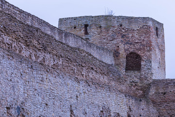The ruines of old ancient medieval fortress or castle with turret or tower and brick, cobble or stone wall in the cloudy spring or autumn day © Майджи Владимир