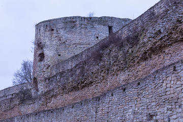 The ruines of old ancient medieval fortress or castle with turret or tower and brick, cobble or stone wall in the cloudy spring or autumn day © Майджи Владимир