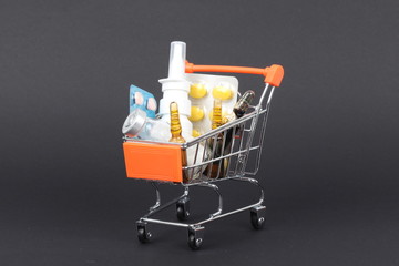 Shopping trolley with pills and medicine isolated on black