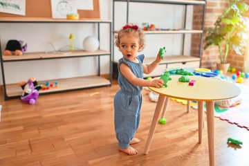 Beautiful caucasian infant playing with toys at colorful playroom. Happy and playful at kindergarten.