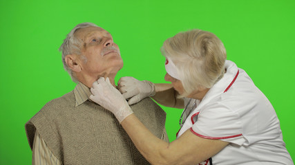 Mature woman nurse doctor examines senior patient man with problems