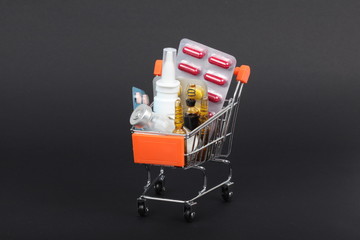 Shopping trolley with pills and medicine isolated on black