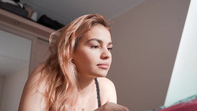 Very beautiful mixed race woman typing on laptop at home. Handsome female lying on bed surfing compter. Casually smiling and being cute. 