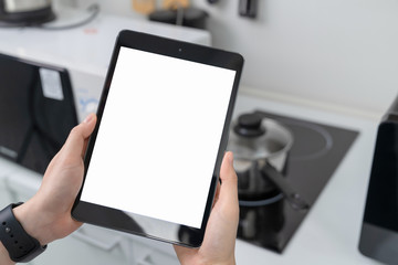 Close-up of hand holding digital tablet at home in kitchen.