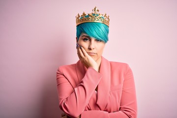 Young business woman with blue fashion hair wearing queen crown over pink isolated background thinking looking tired and bored with depression problems with crossed arms.