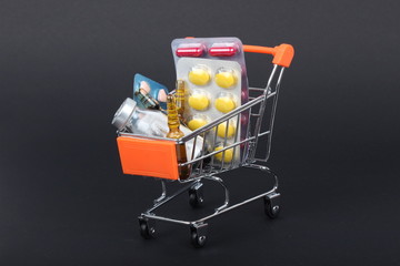 Shopping trolley with pills and medicine isolated on black