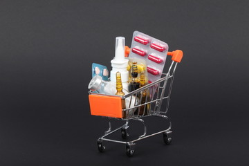 Shopping trolley with pills and medicine isolated on black