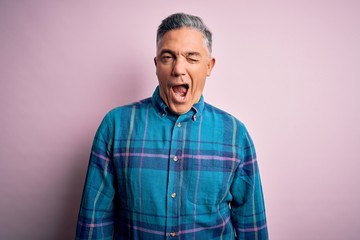 Obraz premium Middle age handsome grey-haired man wearing casual shirt over isolated pink background winking looking at the camera with sexy expression, cheerful and happy face.