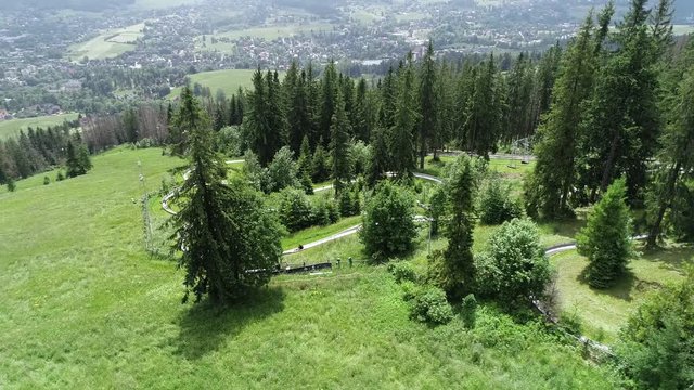 Aerial view of bobsleigh track on green mountain hill. Downhill with summer bobsleigh. Summer toboggan run or bobsleigh track