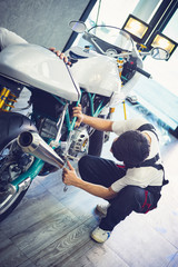 Asian mechanic man fixing the retro motorcycle in the garage. Film effected - Selective focused