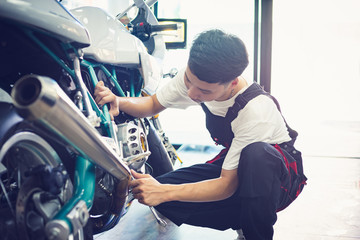 Asian mechanic man fixing the retro motorcycle in the garage. Film effected - Selective focused
