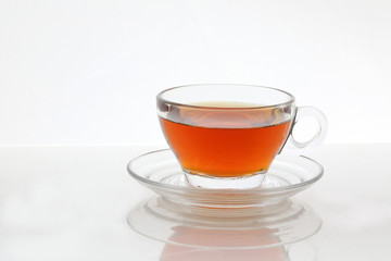 Clear licker tea in a transparent glass cup saucer spoon on white background
