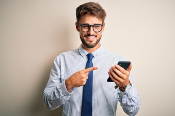 Young businessman having a conversation using smartphone over white background very happy pointing with hand and finger