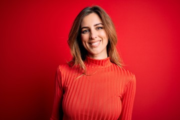 Young beautiful brunette woman wearing casual turtleneck sweater over red background with a happy and cool smile on face. Lucky person.