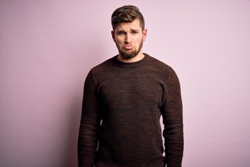 Obraz premium Young blond man with beard and blue eyes wearing casual sweater over pink background depressed and worry for distress, crying angry and afraid. Sad expression.
