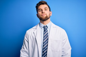 Young blond therapist man with beard and blue eyes wearing coat and tie over background Relaxed with serious expression on face. Simple and natural looking at the camera.