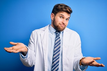 Young blond therapist man with beard and blue eyes wearing coat and tie over background clueless and confused expression with arms and hands raised. Doubt concept.