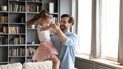 Happy dad and preschooler daughter dance have fun at home