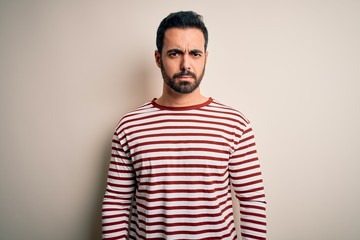 Obraz premium Young handsome man with beard wearing casual striped t-shirt standing over white background skeptic and nervous, frowning upset because of problem. Negative person.