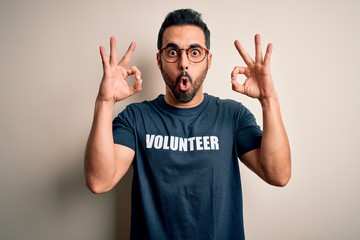 Handsome man with beard wearing t-shirt with volunteer message over white background looking...